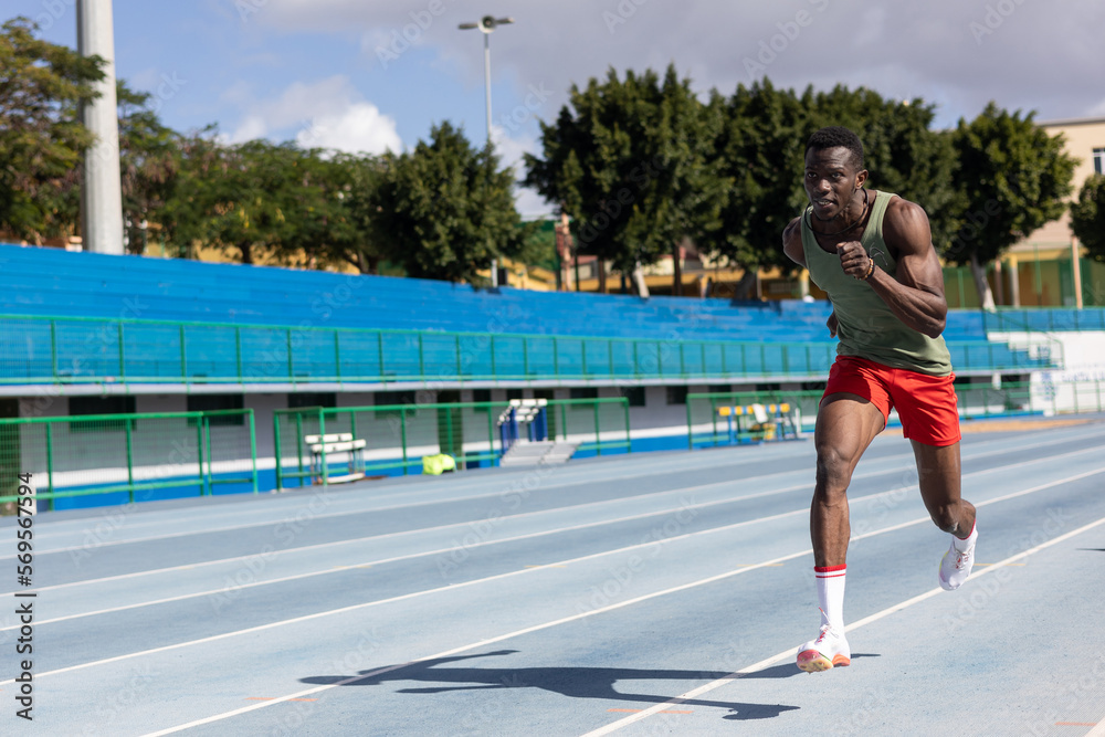african man running on athletics track