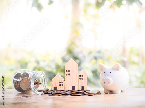 Miniature house on stack of coins and piggy bank for Investment property concept. Saving money for buy a house.