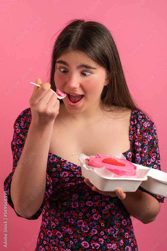 Funny teen girl eating bento cake. Studio shot on pink background Funny teen girl eating bento cake. Studio shot on pink background