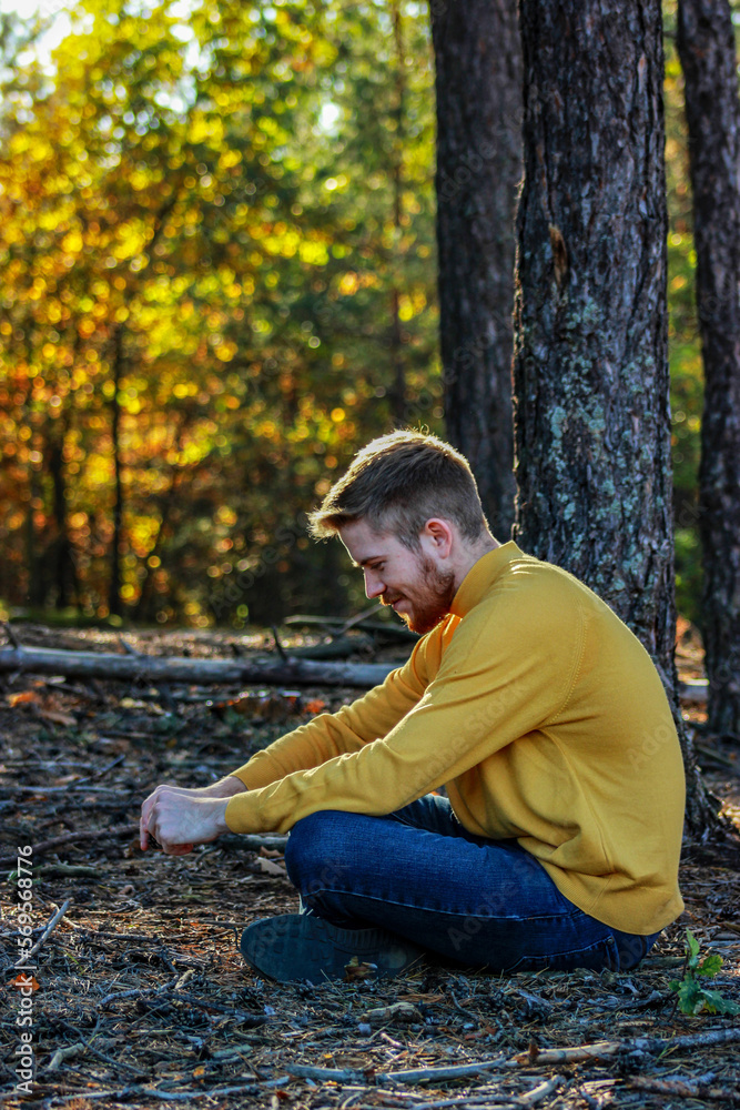 Bearded man in the forest sitting on the ground