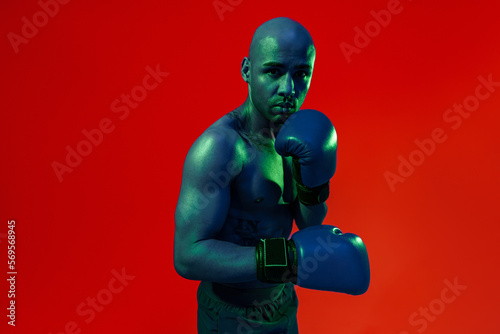 Portrait of sporty man wearing boxing gloves practicing for fight on studio background