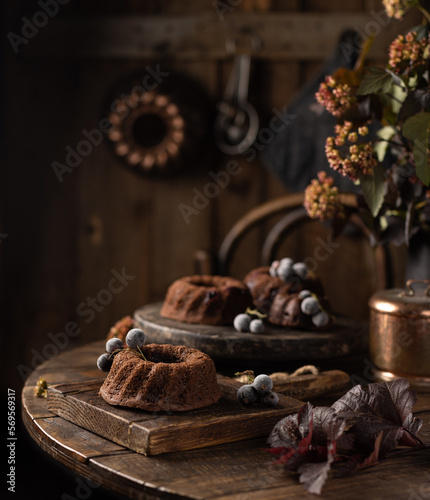 Homemade chocolate bundt cakes with berries on wooden table.Delicious dessert photo in rustic style.