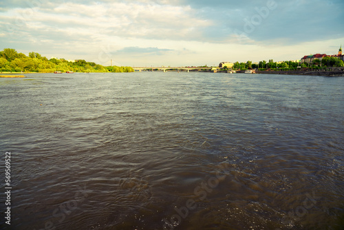 Wide river landscape with calm water surface under partly cloudy sky. Green shoreline and distant horizon visible. Natural freshwater scenery, travel and environment concept.