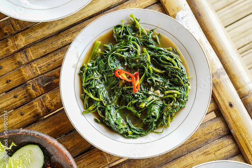 Stir-fried Water Spinach, Morning Glory, Stir-fried Kale, tumis kangkung served on a white plate photo