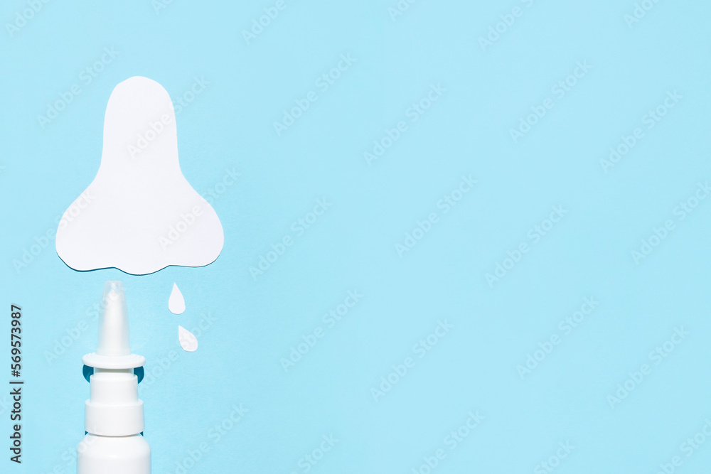 Paper silhouette of a nose and a can of spray on a blue background. Concept against allergic nasal congestion. Paper silhouette of a nose and a can of spray on a blue background. Concept against allergic nasal congestion.