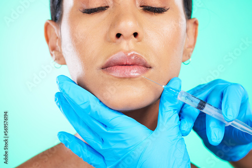 Woman  face and hands with syringe for plastic surgery  lip implants or botox isolated on a studio background. Hand of doctor with needle injecting filler on female lips for facial cosmetic treatment