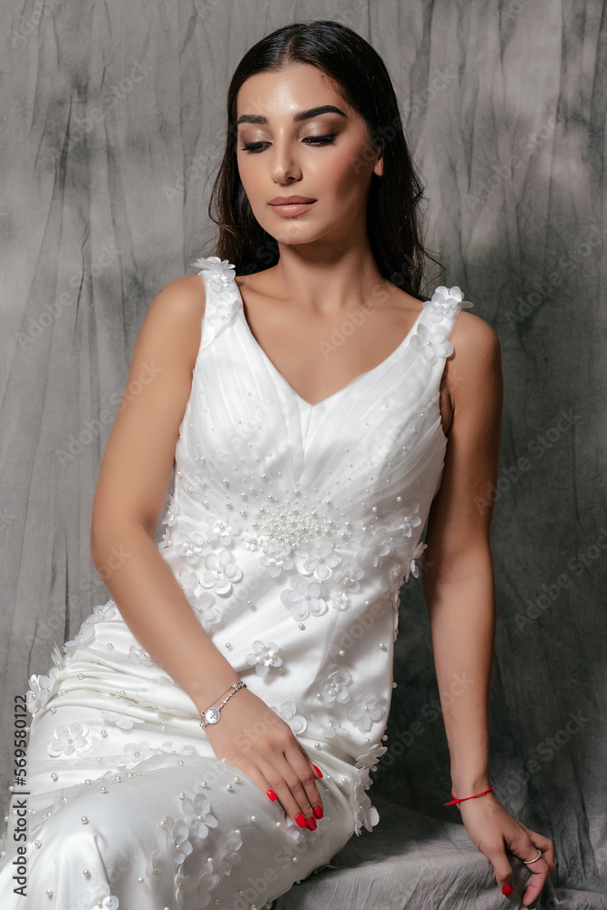 Fototapeta premium Girl in a wedding dress studio portrait on a gray background