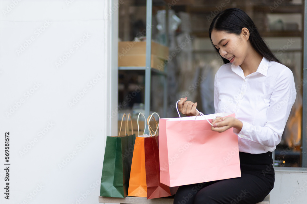 Asian woman holding a bill checking shopping bags after shopping at a street market in Thailand. Asian woman holding a bill checking shopping bags after shopping at a street market in Thailand.