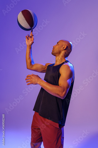 Professional basketball player spinning ball on his finger on studio background © Kostiantyn