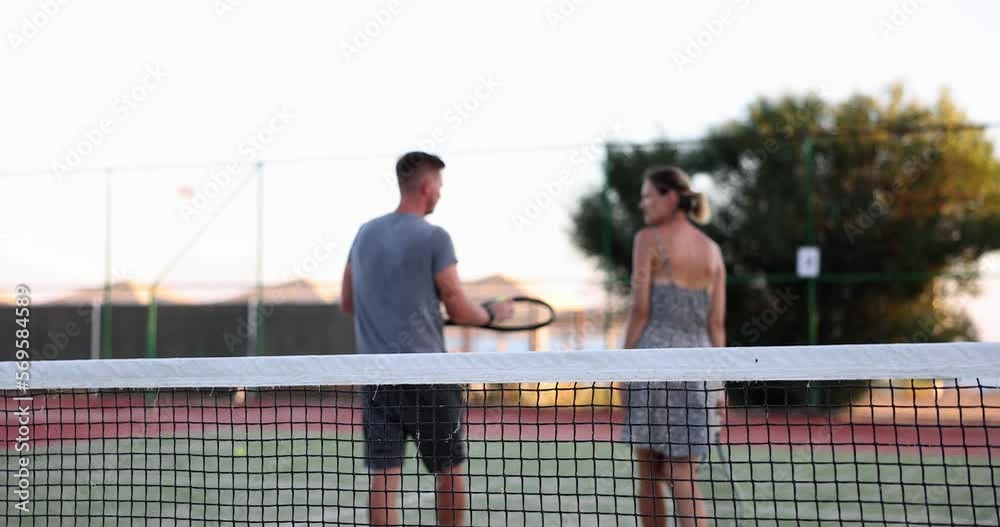 Couple of tennis players are walking on tennis court rear view Couple of tennis players are walking on tennis court rear view