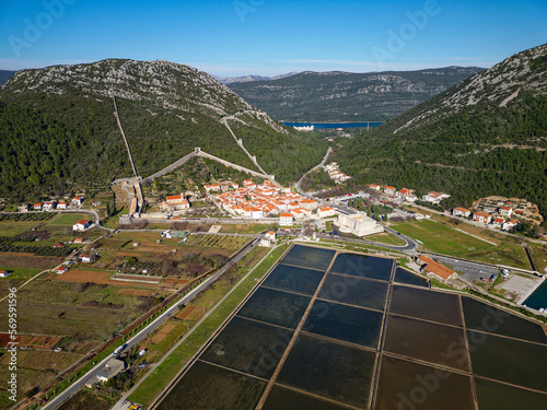 Aerial drone view of the salt pan in the city of Ston in Croatia. Fortified walls in the hills in the background. Salt fields. Ston Salt Works. Tourism near the Adriatic sea. Historic visits. 