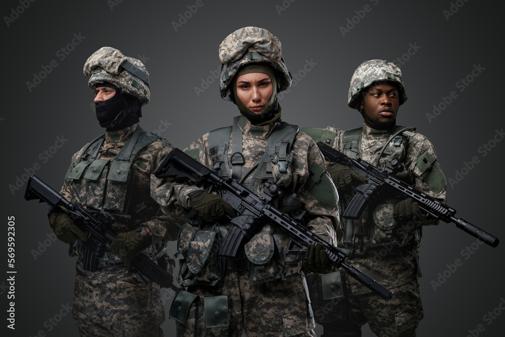 Brave female soldiers with two comrades looking at camera isolated on grey. Brave female soldiers with two comrades looking at camera isolated on grey.