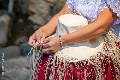 Ecuadorian indigenous chola woman weaving Panama hat from Toquilla palm leaf fiber, Cuenca, Ecuador. photo