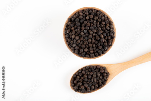 Black pepper grains in a bowl on a white background