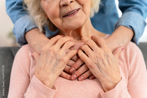 Cropped view of the loving grown up daughter hugging senior mother from back. Happy mature grandmother posing for family photo at home