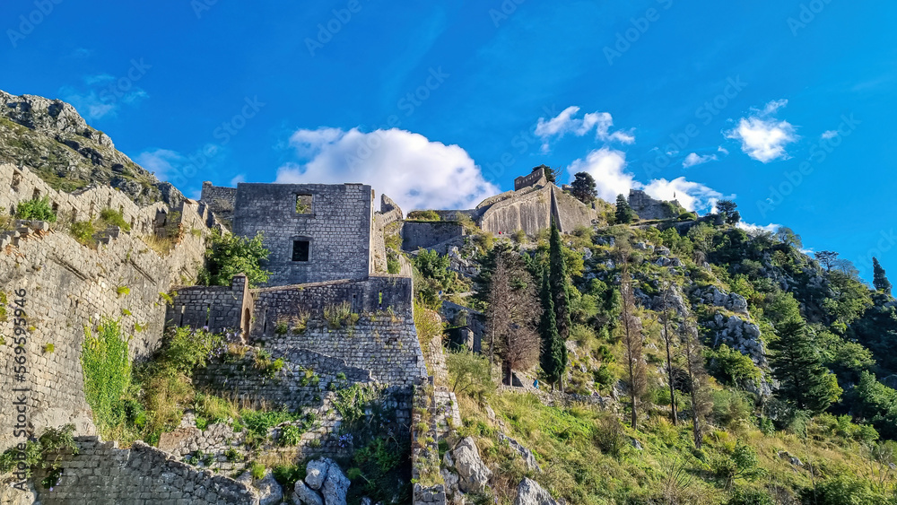 Fototapeta premium Old medieval ruin of castle on Kotor city wall in Montenegro, Balkan Peninsula, Europe. Lovcen and Orjen mountains, Dinaric alps. Hiking trail to San Giovanni fortress. Historical landmark. Tourism