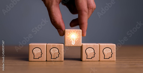 brainstorming creative idea and innovation. Hand putting over wooden cube block with light bulb icon on many people together having an idea symbolized by icons on cubes.