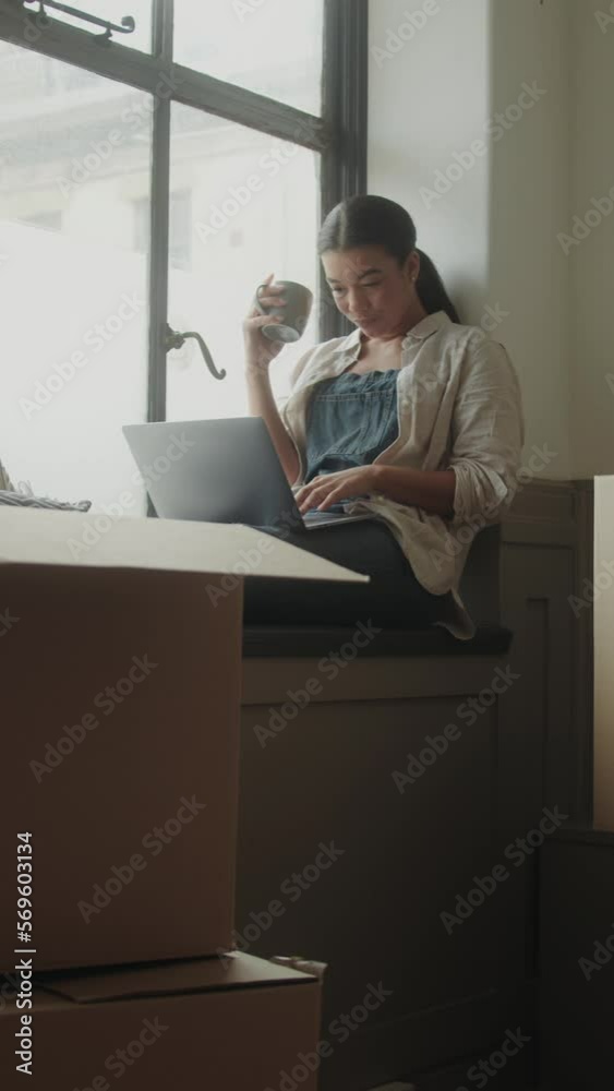 Adult Female using Laptop in New Home Planning Surrounded by Boxes Adult Female using Laptop in New Home Planning Surrounded by Boxes