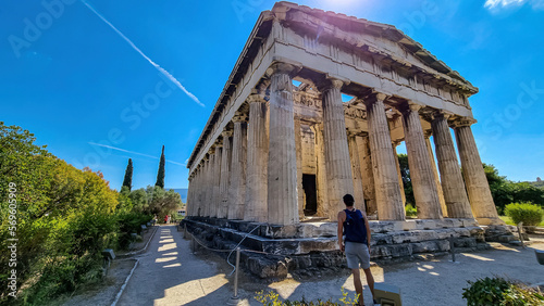Rear view of tourist man standing in front of the temple of Hephaestus and Athena Ergane Agora, Athens, Attica, Greece, Europe. Cultural walk around the remain ruins of ancient agora. photo