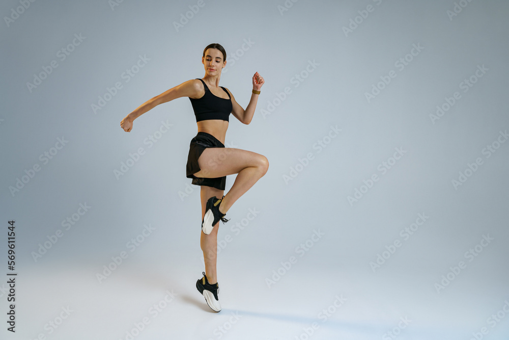 Athletic active woman jumping on studio background . Dynamic movement