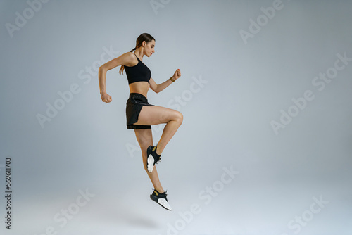 Athletic active woman jumping on studio background . Dynamic movement