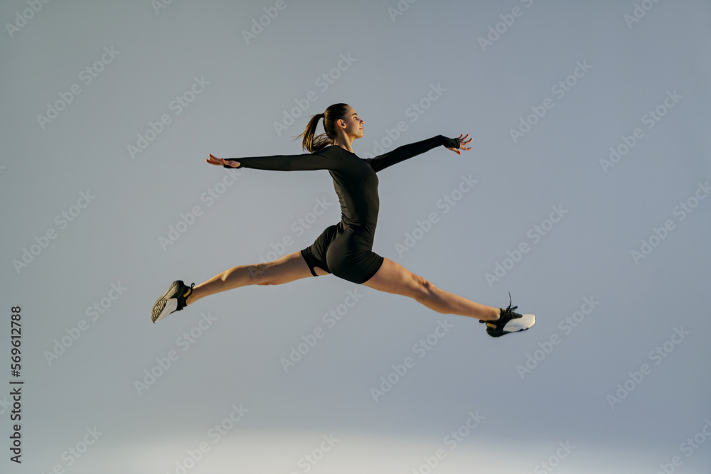Athletic active woman jumping on studio background with colored filter. Dynamic movement Athletic active woman jumping on studio background with colored filter. Dynamic movement