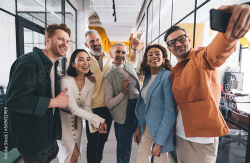 Joyful multiethnic colleagues taking selfie on smartphone