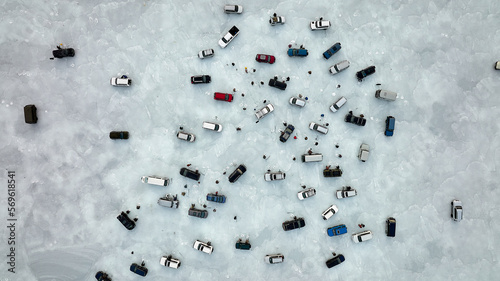 Colorful cars stand on transparent blue ice ice there are many people involved in ice fishing
