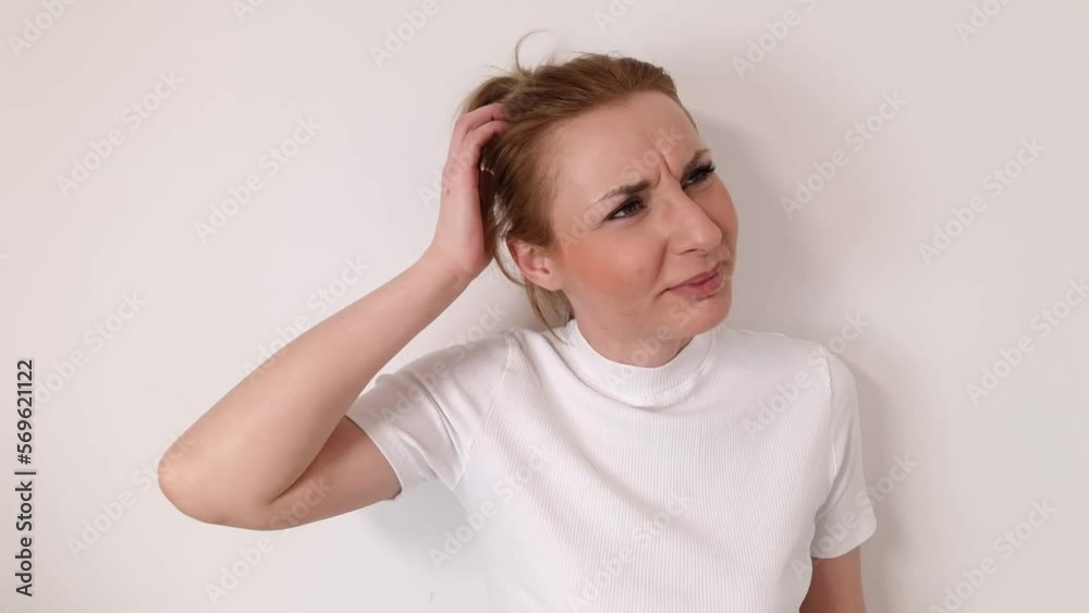 Clueless uncertain woman in white t-shirt scratching head, feeling confused. She is unsure about answer, having doubts, difficult choice