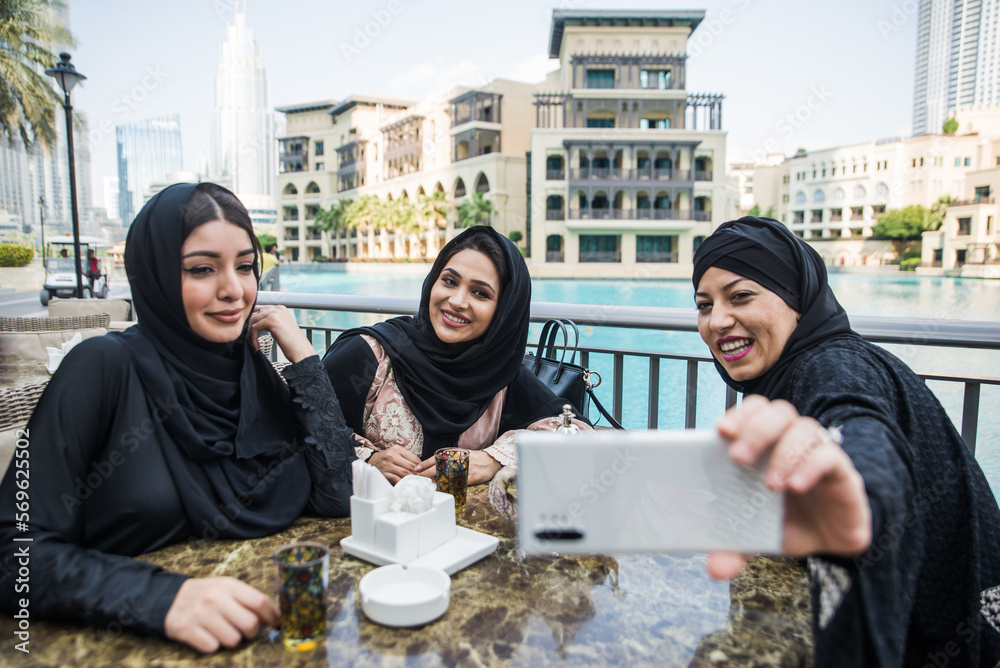 Three women friends going out in Dubai. Girls wearing the united arab emirates traditional abaya Three women friends going out in Dubai. Girls wearing the united arab emirates traditional abaya