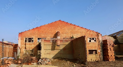 Ruins of an abandoned factory with damaged brick walls and smashed windows under blue sky. Western de industrialization
