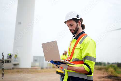 engineer with laptop at wind turbine site.