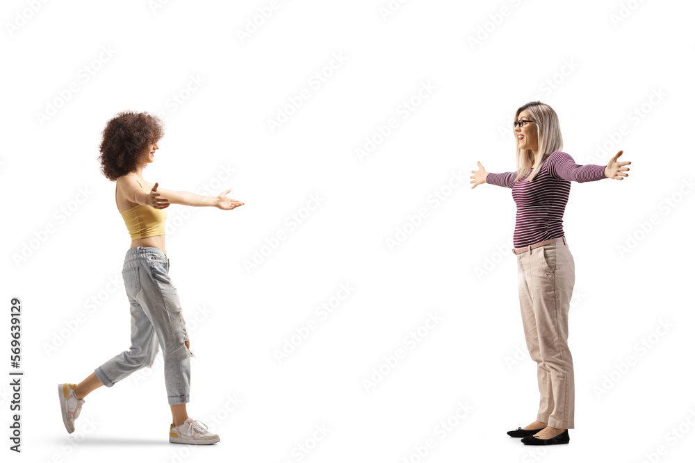 Full length profile shot of two young women meeting and greeting each other Full length profile shot of two young women meeting and greeting each other