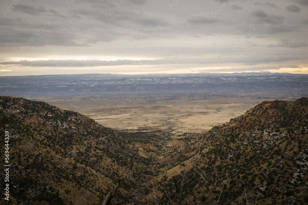 Obraz premium Wide view of mountain valley in Grand Junction Colorado overlooked flat desert and snow covered mesas