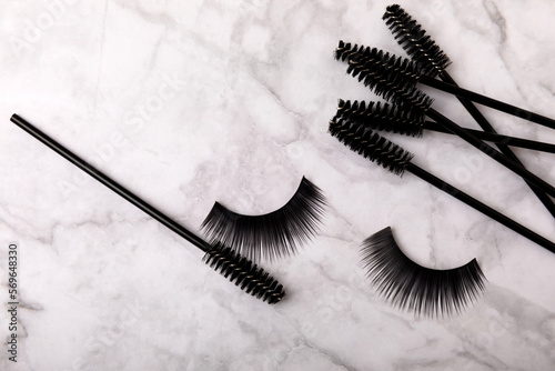 Foto Composition with mascara and eyelash brushes, false eyelashes on a textured background
