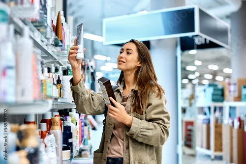 Obraz Smiling woman looking for skin care products at cosmetic store.