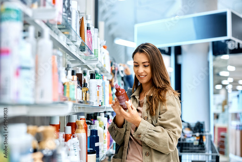 Fotografie Happy woman reads label on skin care product while shopping at mall
