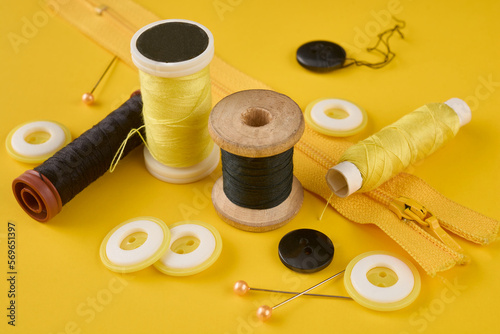 On a yellow background are different spools of black and yellow thread