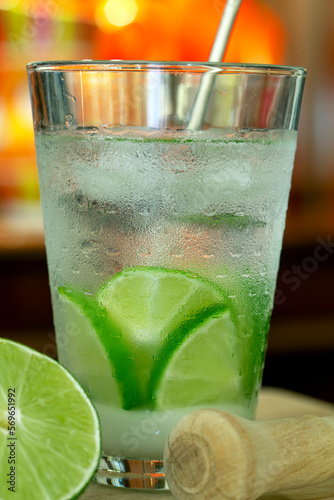 Brazilian traditional drink: Caipirinha with Tahiti lime with blurred colored bottles in the background photo