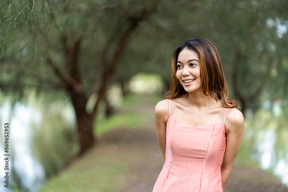 Young woman in pink dress enjoying the tranquil scenery with bokeh park background Young woman in pink dress enjoying the tranquil scenery with bokeh park background
