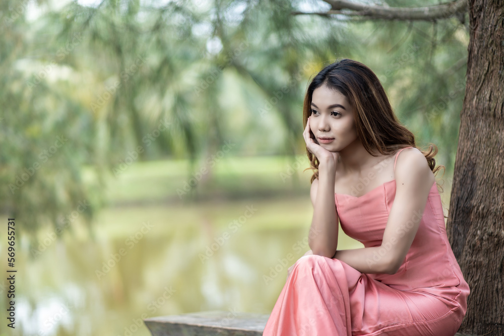 Stunning young woman in pink dress and natural background