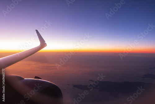 Amazing evening view from the airplane porthole to the sunset, colored sky, wing and turbine. Airplane travel, creative idea. Transport is flying in the beautiful sky