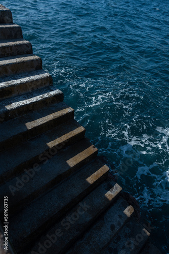 Concrete steps lead to the ocean on a sunny day. Minimalism photo with light and shadows