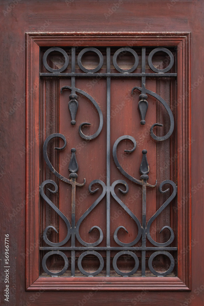 close-up of a beautiful black forged fence on a window with shutters in a old house close-up of a beautiful black forged fence on a window with shutters in a old house