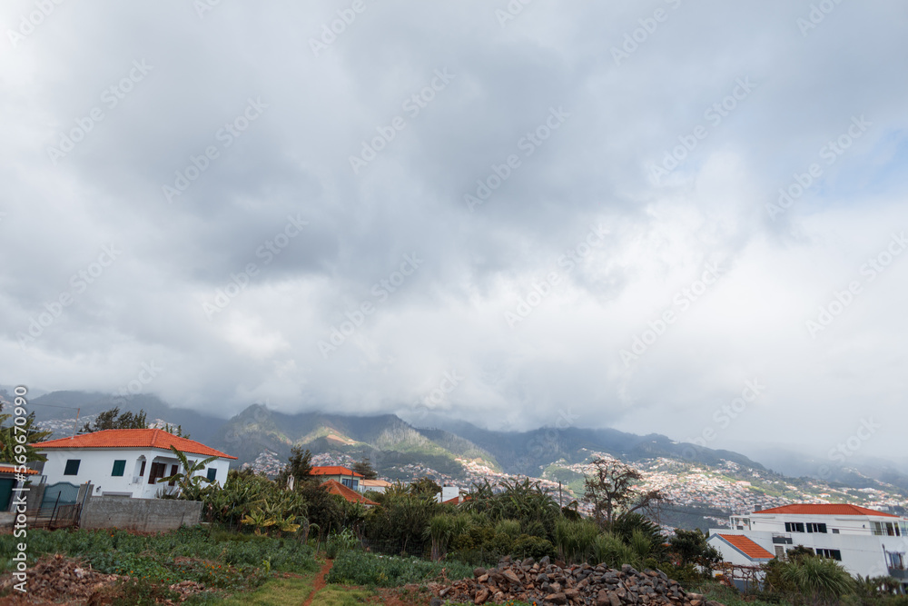 Beautiful mountain landscapes with houses on a cloudy day with clouds. Madeira island and hills