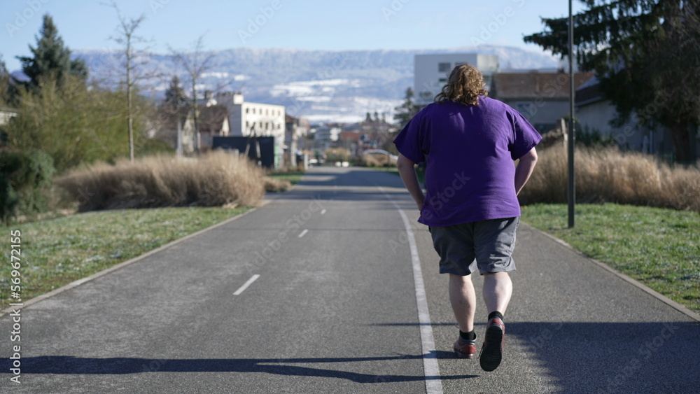 Back of One young overweight man jogging outdoors. Tracking shot of a chubby male person running. Getting back to shape concept