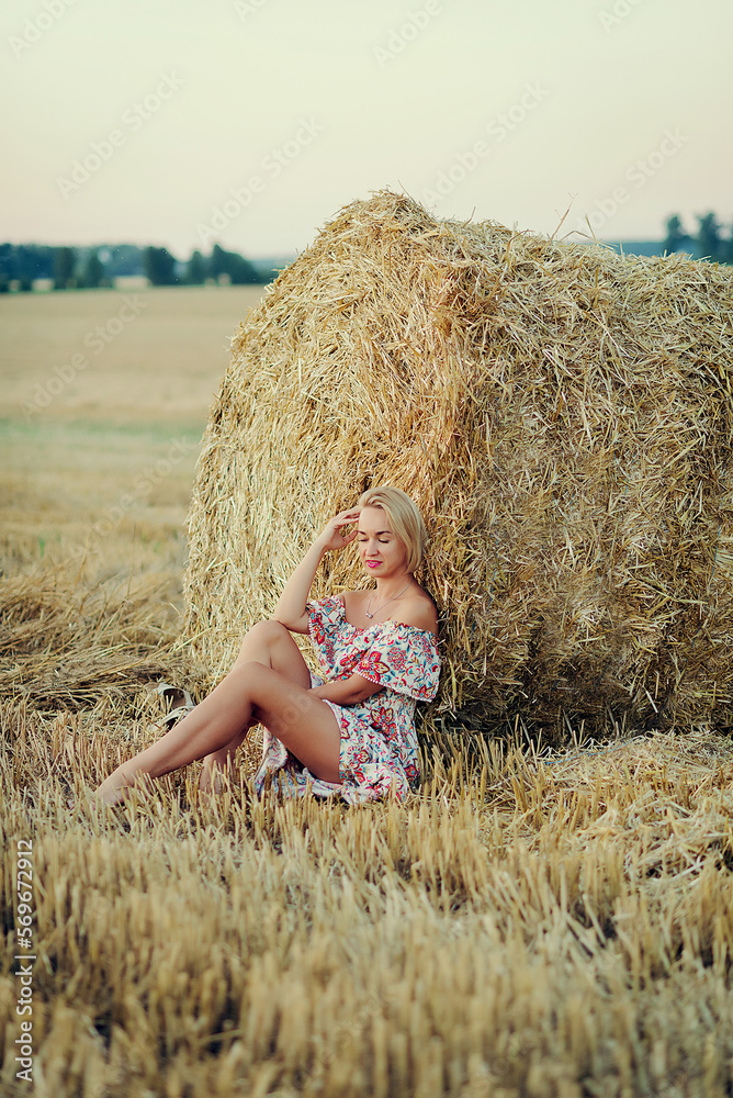 Young beautiful woman sits with closed eyes on haystack . Countryside holiday Young beautiful woman sits with closed eyes on haystack . Countryside holiday