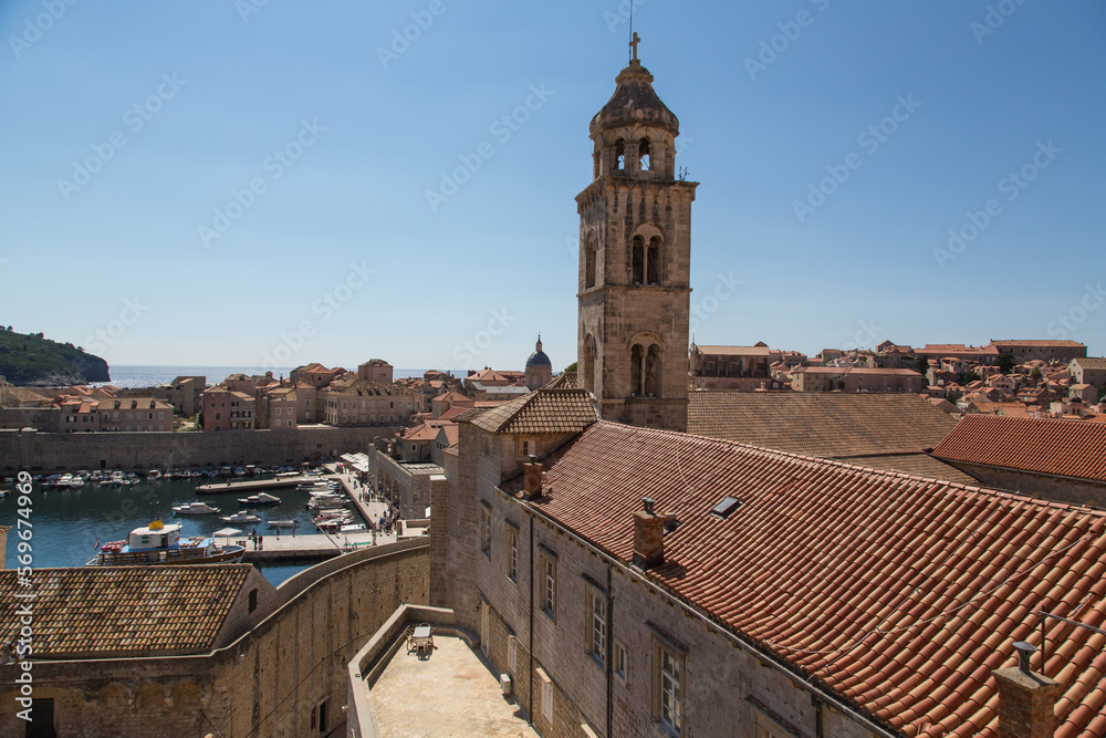 Walk along the old wall with view to the Dominican monastery, its bell tower and the old town with the  old harbor of Dubrovnik, Croatia 