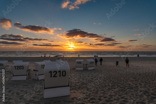 A group of beach chairs with tourists and the beach view into the sunset, Baltic Sea, Sylt, Germany. photo