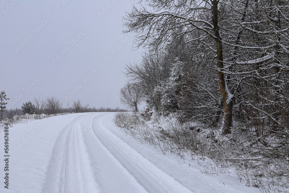 Scenic view of empty, not cleared road with snowy landscape during snowfall in winter season. Right turn onto a slippery winter road. A gloomy winter day. Ukraine. Scenic view of empty, not cleared road with snowy landscape during snowfall in winter season. Right turn onto a slippery winter road. A gloomy winter day. Ukraine.